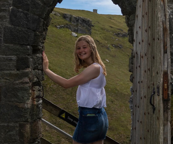 Hannah standing under an archway door smiling at camera