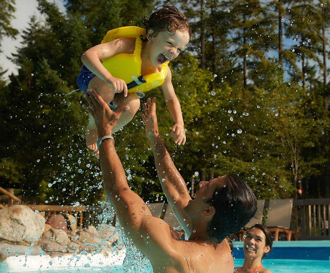 Father holding child high above head in pool