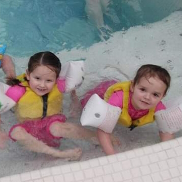 two-sisters-having-fun-in-the-pool-with-armbands-on