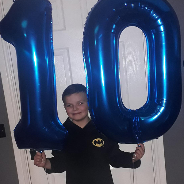 young-boy-smiling-holding-number-ten-balloon