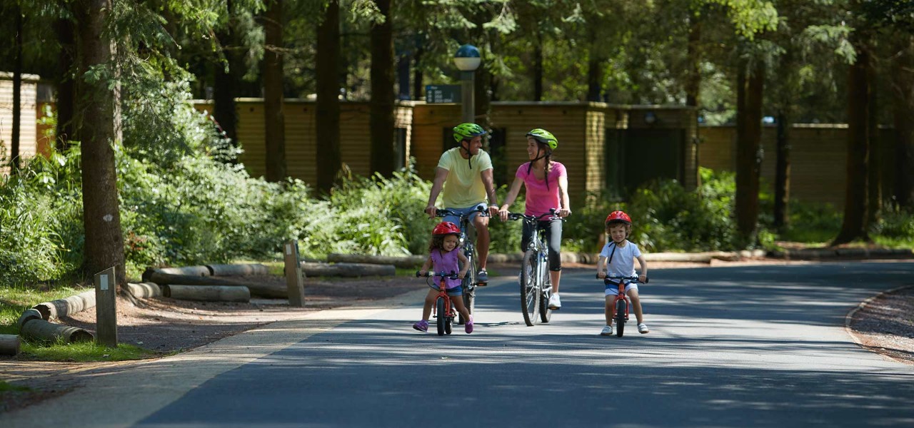 Family riding bikes past a collection of lodges