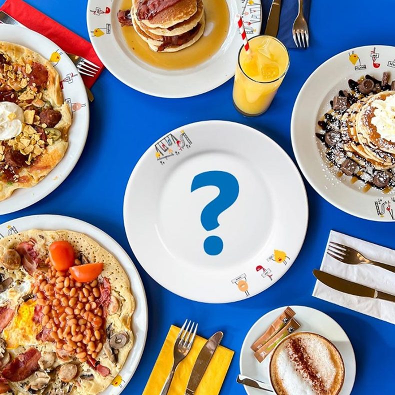 A variety of sweet and savoury pancakes surround an empty plate with a question mark