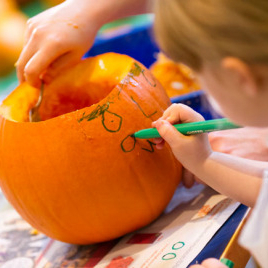 little girl drawing on pumpkin