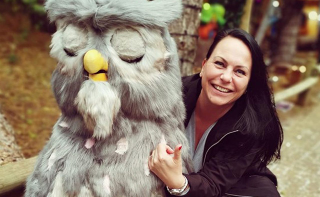 Lisa crouched down next to animatronic The Wise Old Owl