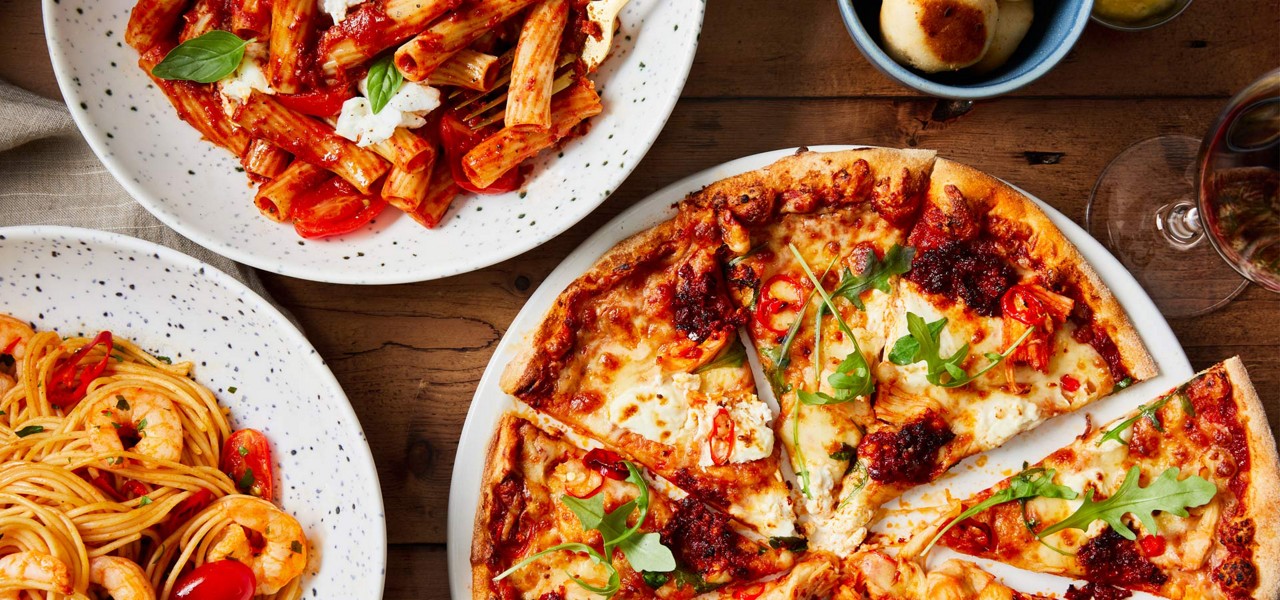 Plates of pizza and pasta on a table
