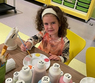 young-girl-with-paintbrush-in-hand-in-pottery-studio