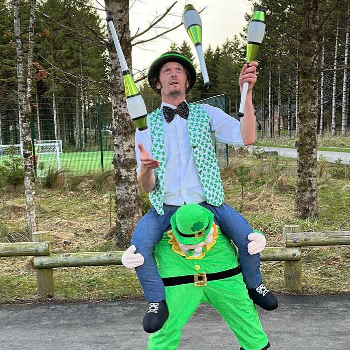 a performer juggles in a green costume