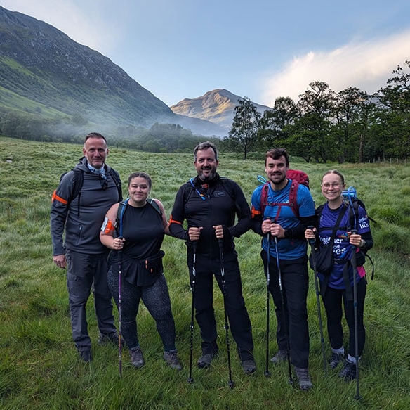 A group of 5 colleagues stood in front of a mountain