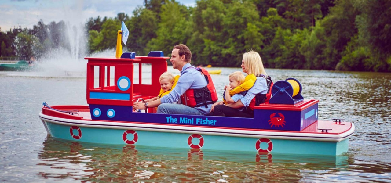 Mum, Dad and two Children ride on a mini captains boat on the lake 