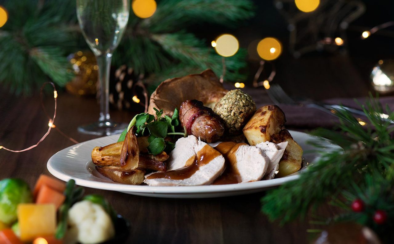 A roast dinner with gravy surrounded by Christmas decorations