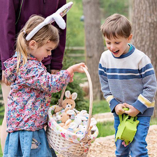 Two children holding a basket of plush bunnies on Easter hunt
