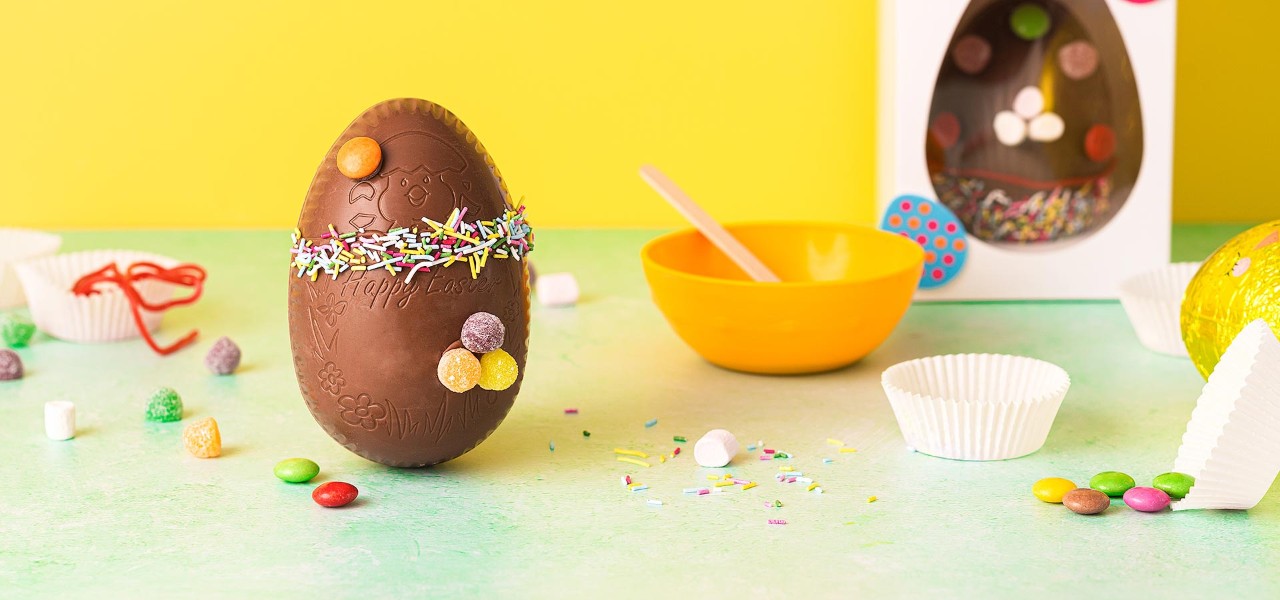 A chocolate Easter Egg surrounded by decorating ingredients