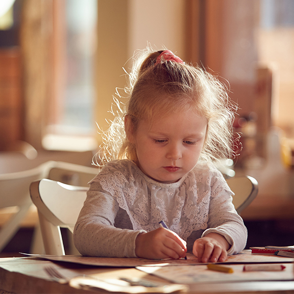 A little girl colouring with crayons at a restaurant