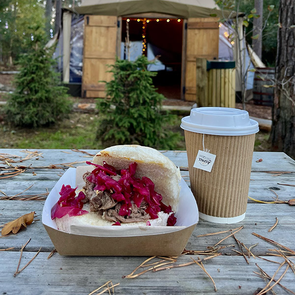 pulled pork brisket in a bun next to a coffee cup with Tipi in the backgroun