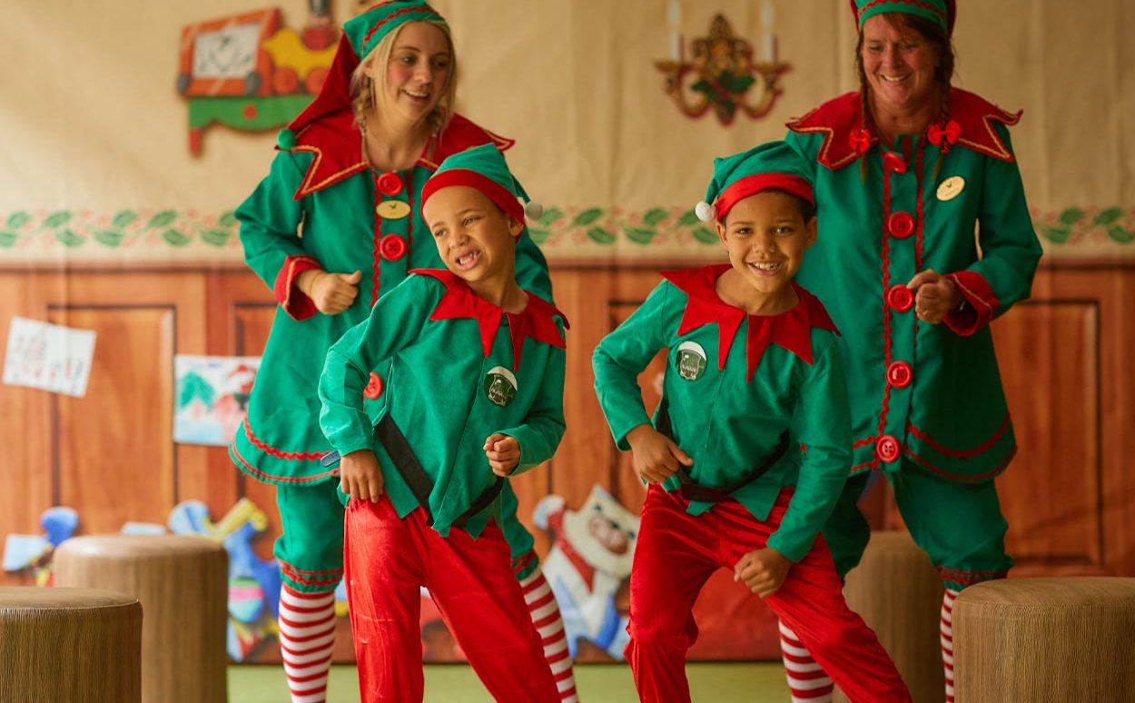 Two little boys dressed in elf costumes dancing with two elves