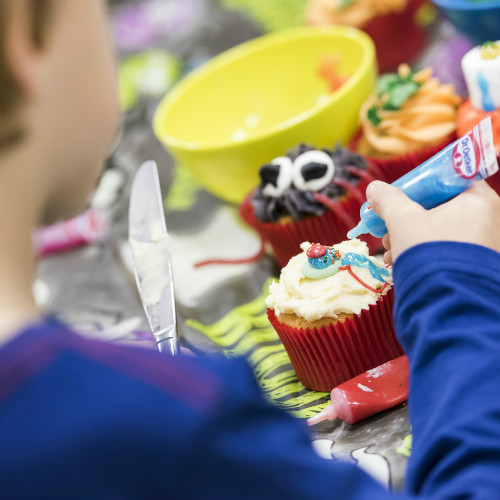 Child decorating Halloween cupcake