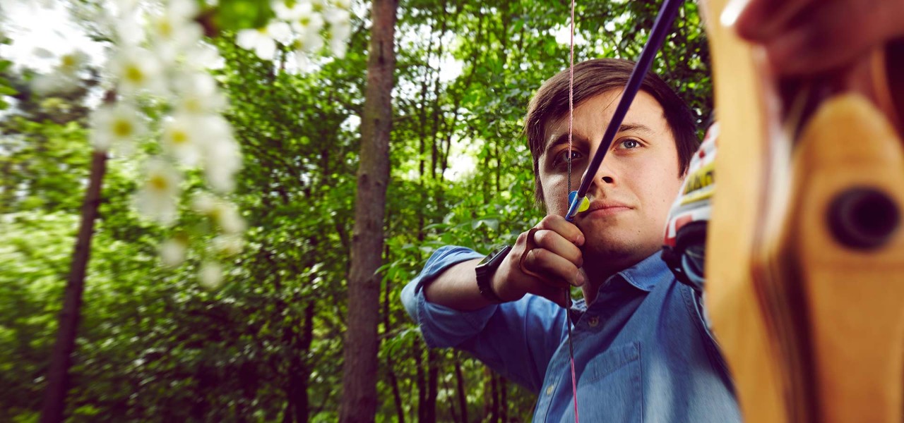 Man looks down arrow whilst taking archery shot