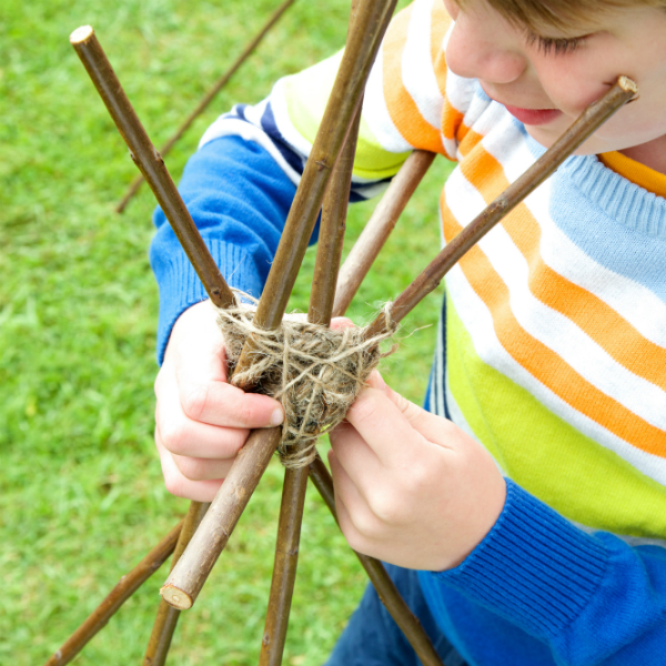 Child using sticks and string to create structure