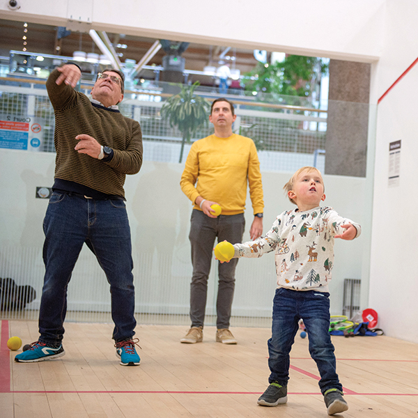Family throwing balls at the interactive squash wall