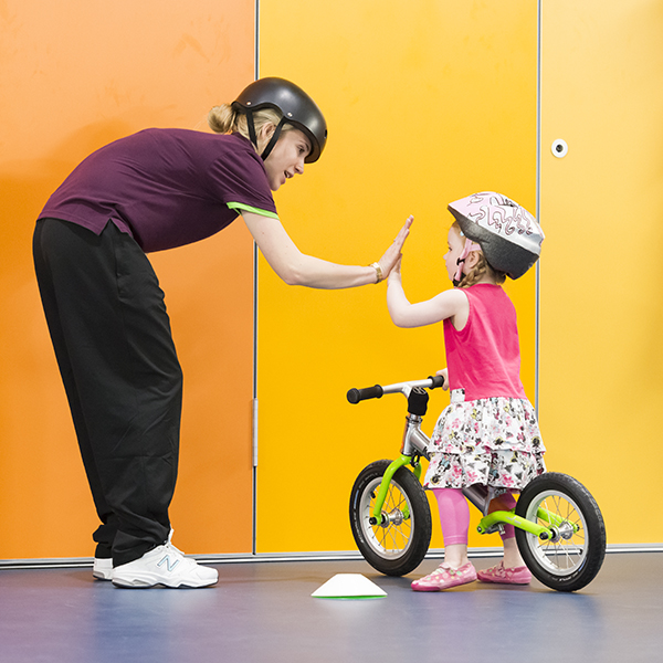 Staff member high-fives a small child on a bike