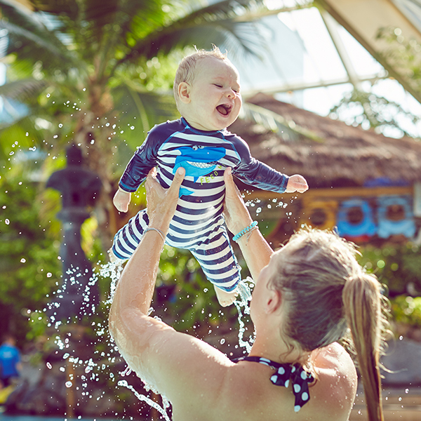 Woman lifts her baby above head in the pool