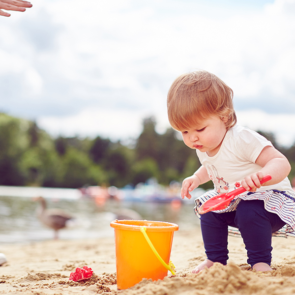 Child on the beach filling a bucket with sand
