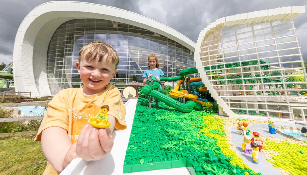 A boy holding a Lego Person next to a model of Longford Forest