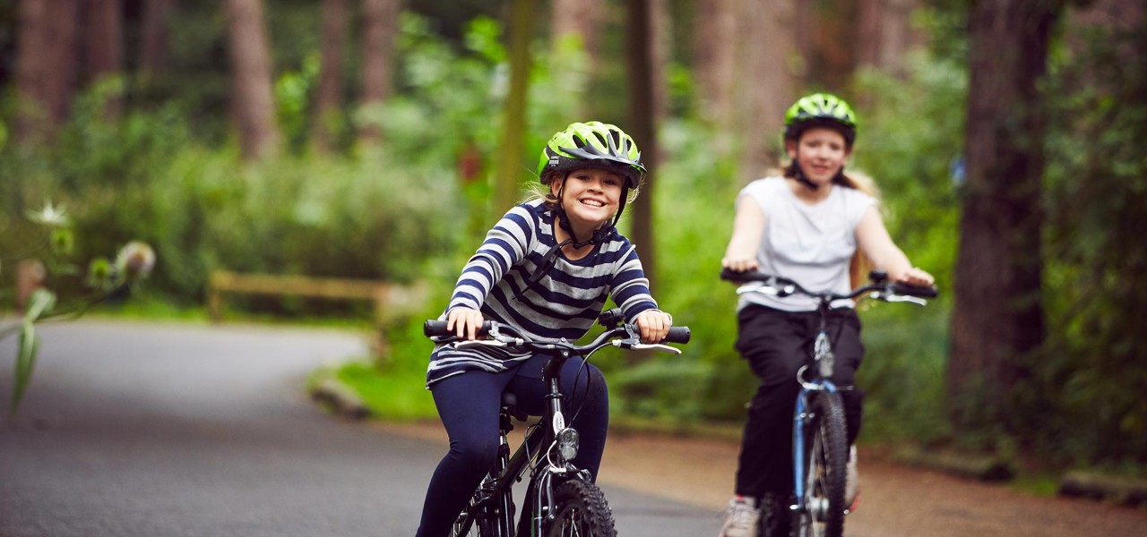 Two girls ride bikes through the forest