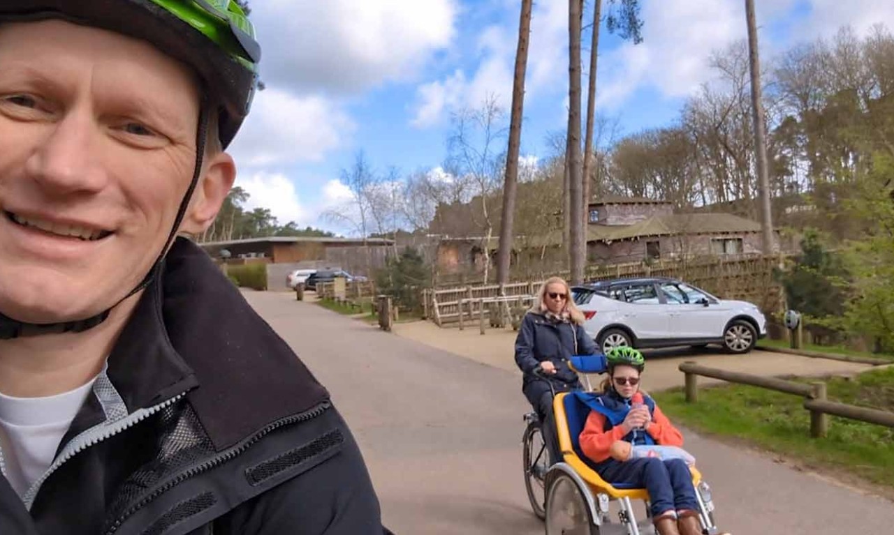 Orla and her parents cycling. Orla and her mum are using a wheelchair bike