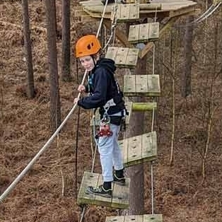 A boy balancing on a wooden plank in Aerial Adventure