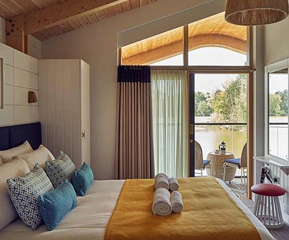 Inside one of our unique Waterside Lodges, a double bed and balcony over looking the lake