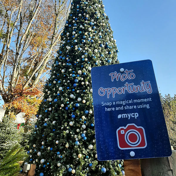 photo opportunity sign in front of a giant Christmas tree covered in baubles