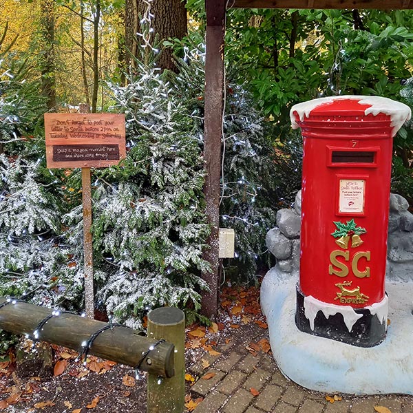 red Santa's post box surrounded by trees sprinkled with snow