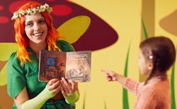 Pixie sat with little girl reading a story 