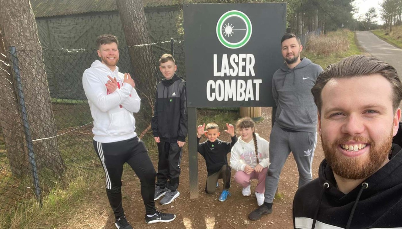 A group photo posing next to the Laser Combat activity sign