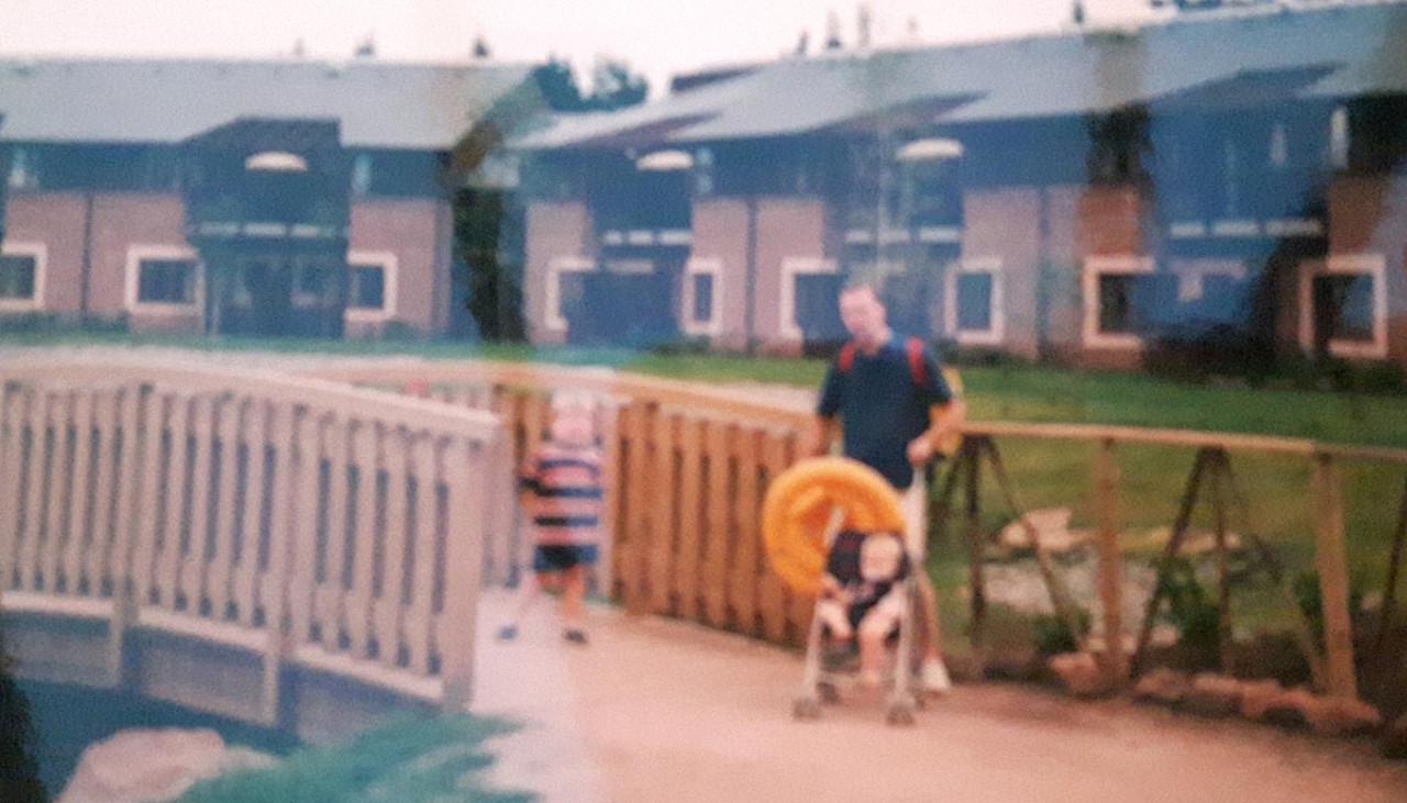 Old photograph of family on path outside apartments