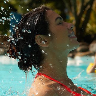 Woman brings head up out of pool, splashing water