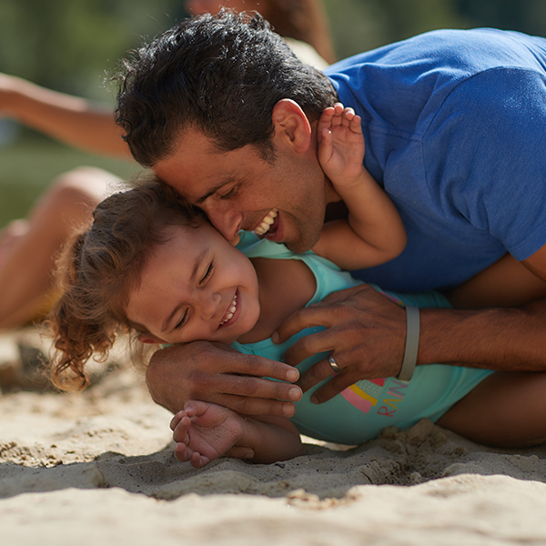 A father and his little girl playing on the sandy beach.