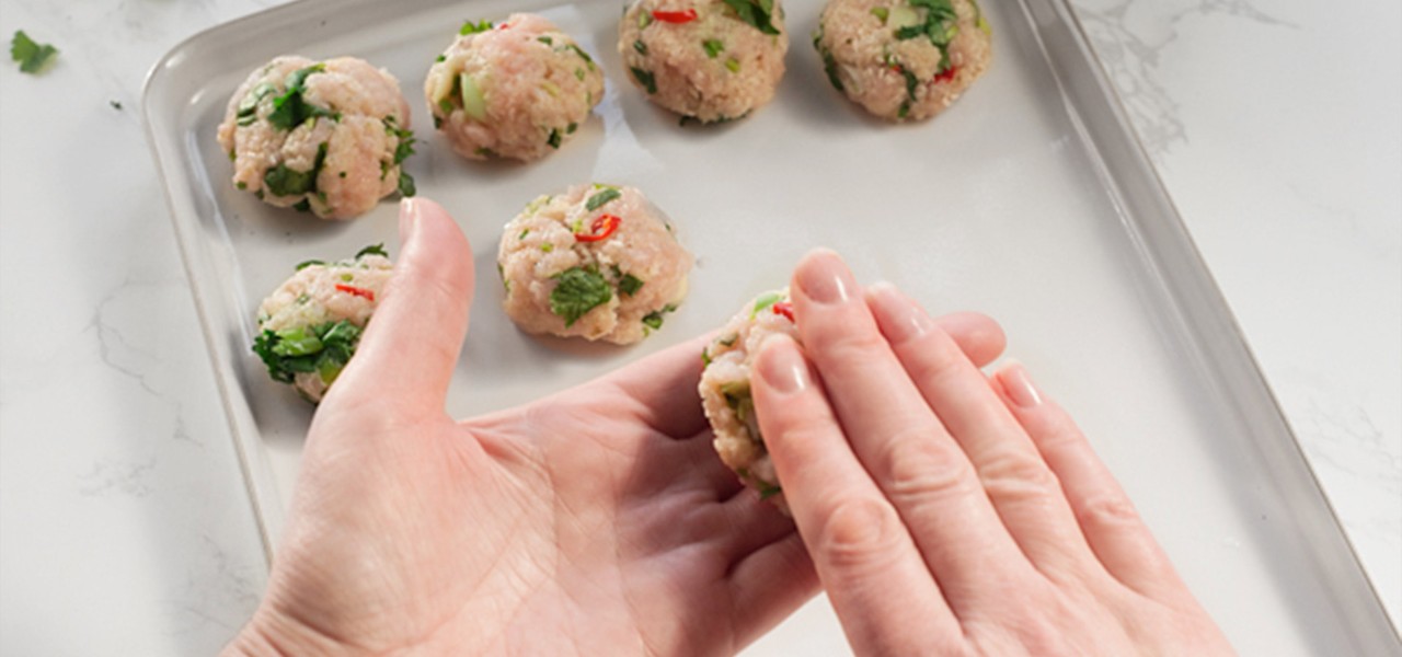 Hands rolling out thai bites into balls onto a tray.