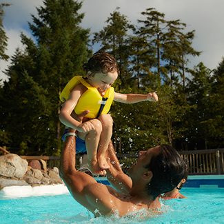 Man holding child high out of pool