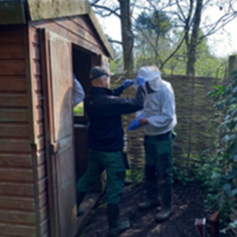 Two beekeepers putting on their beekeeping suits