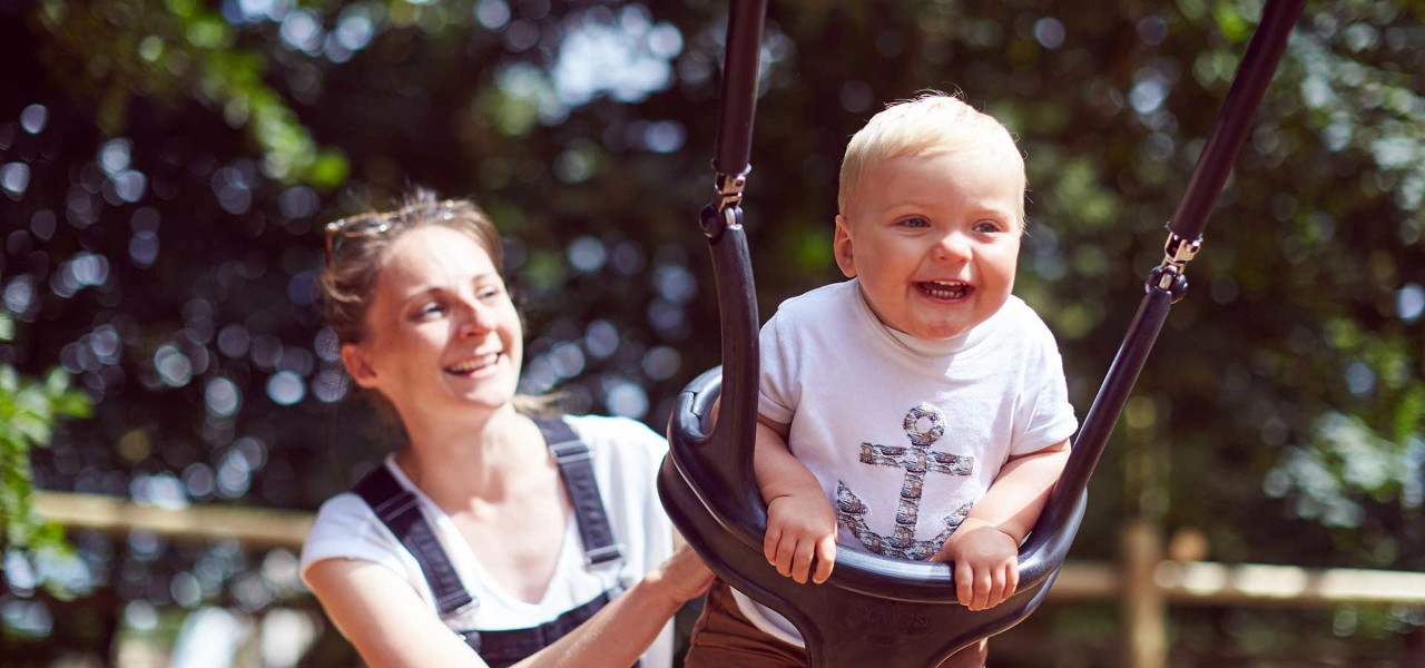 Mother pushing baby on a park swing