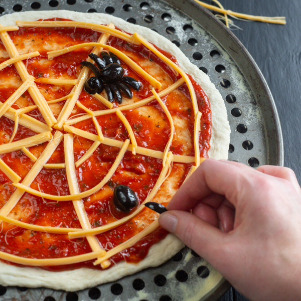Spiders being added to spooky pizza