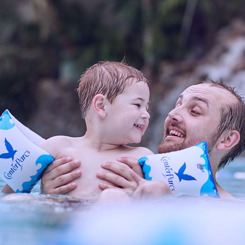 Father holding young boy out of the water