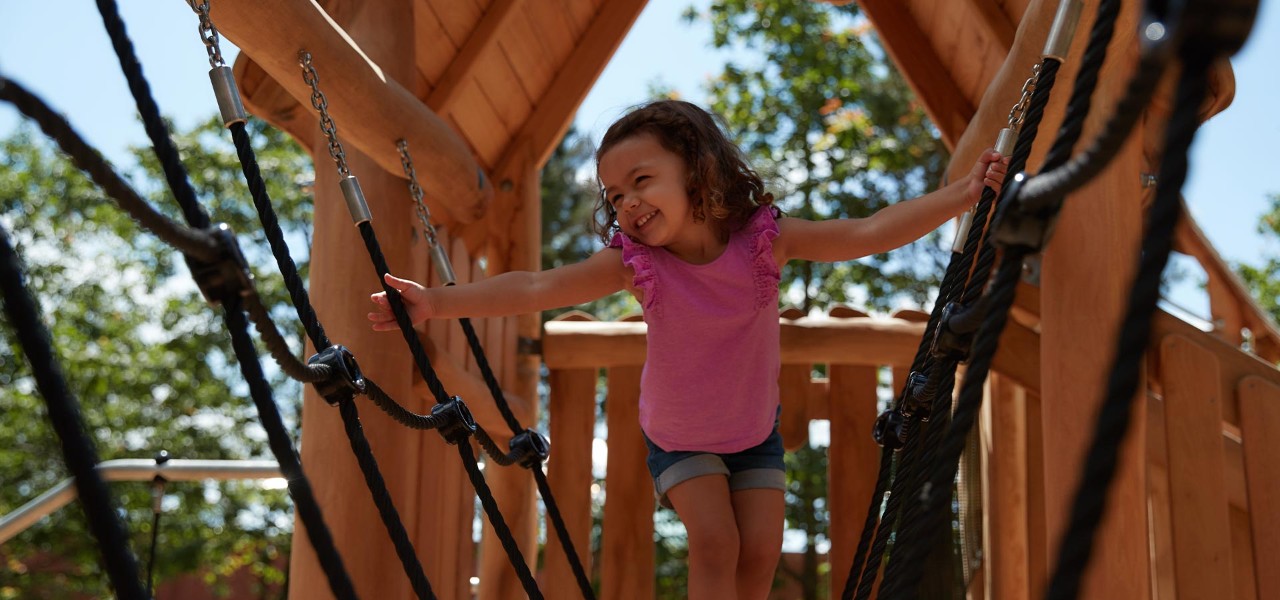 A little girl playing on a wooden climbing frame 