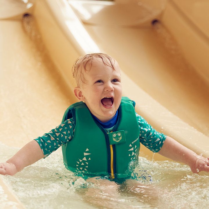 a small child laughs as he goes down a slide