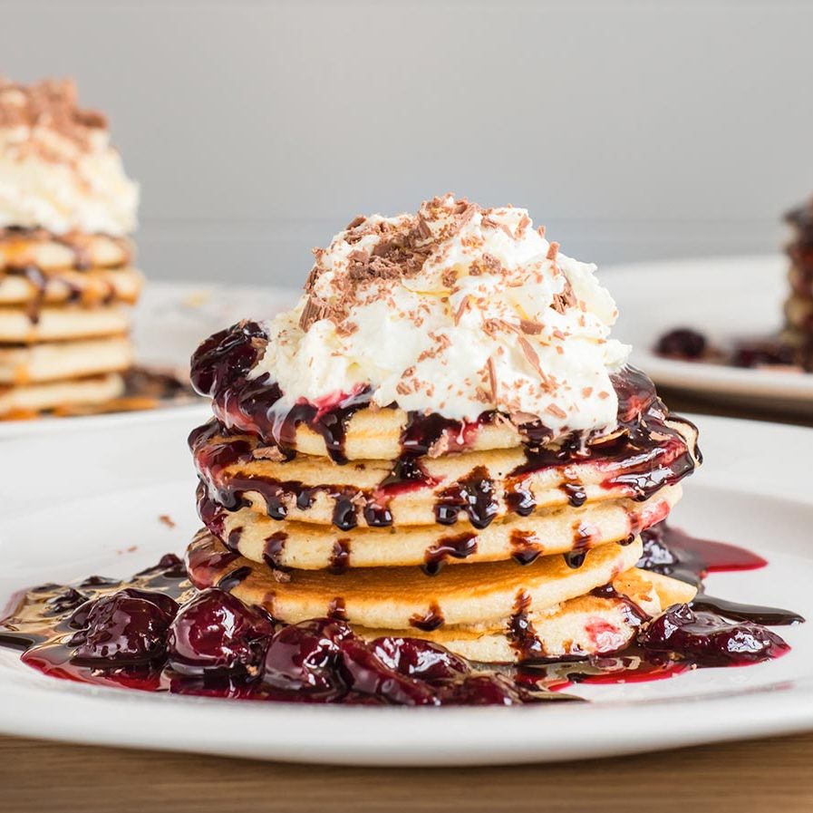 Stack of pancakes with berries and cream