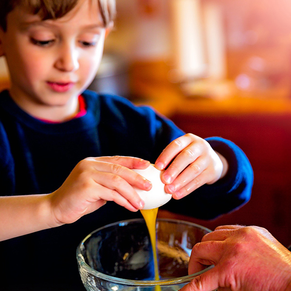 Child cracks an egg into a bowl