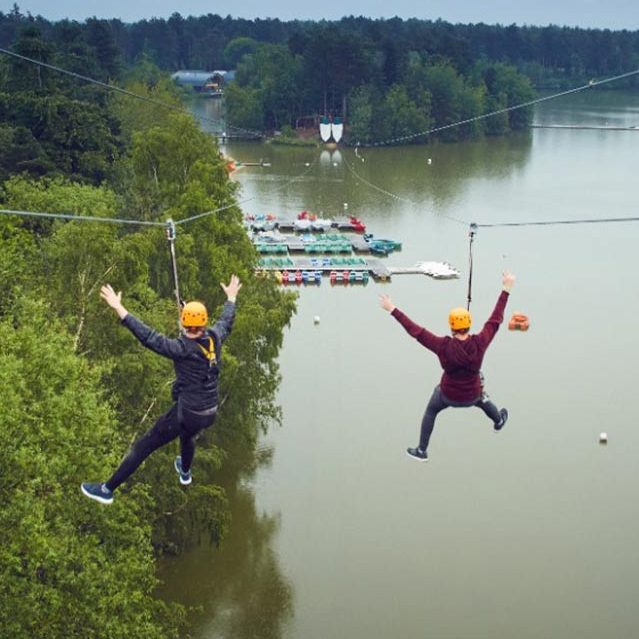 Two teenagers ride the zipwire over the lake 