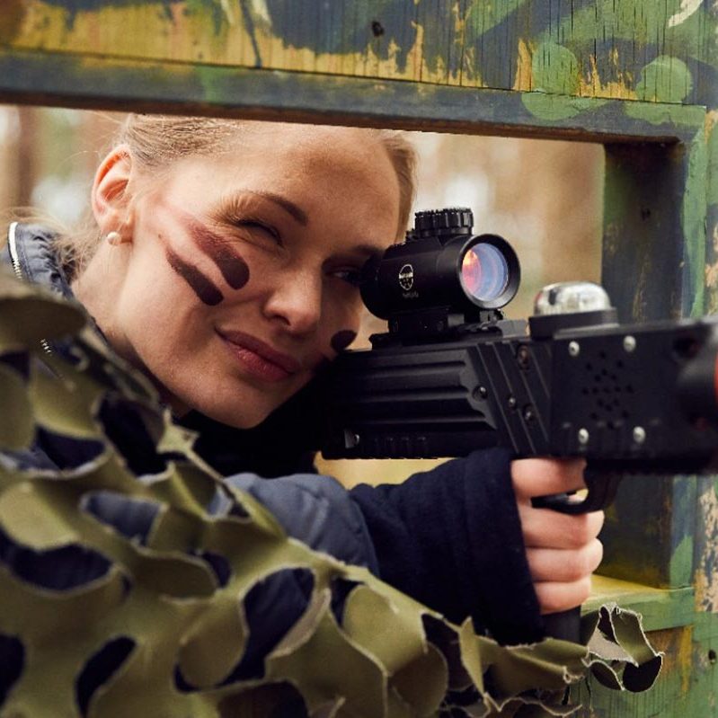 A woman taking aim behind cover at Laser Combat 